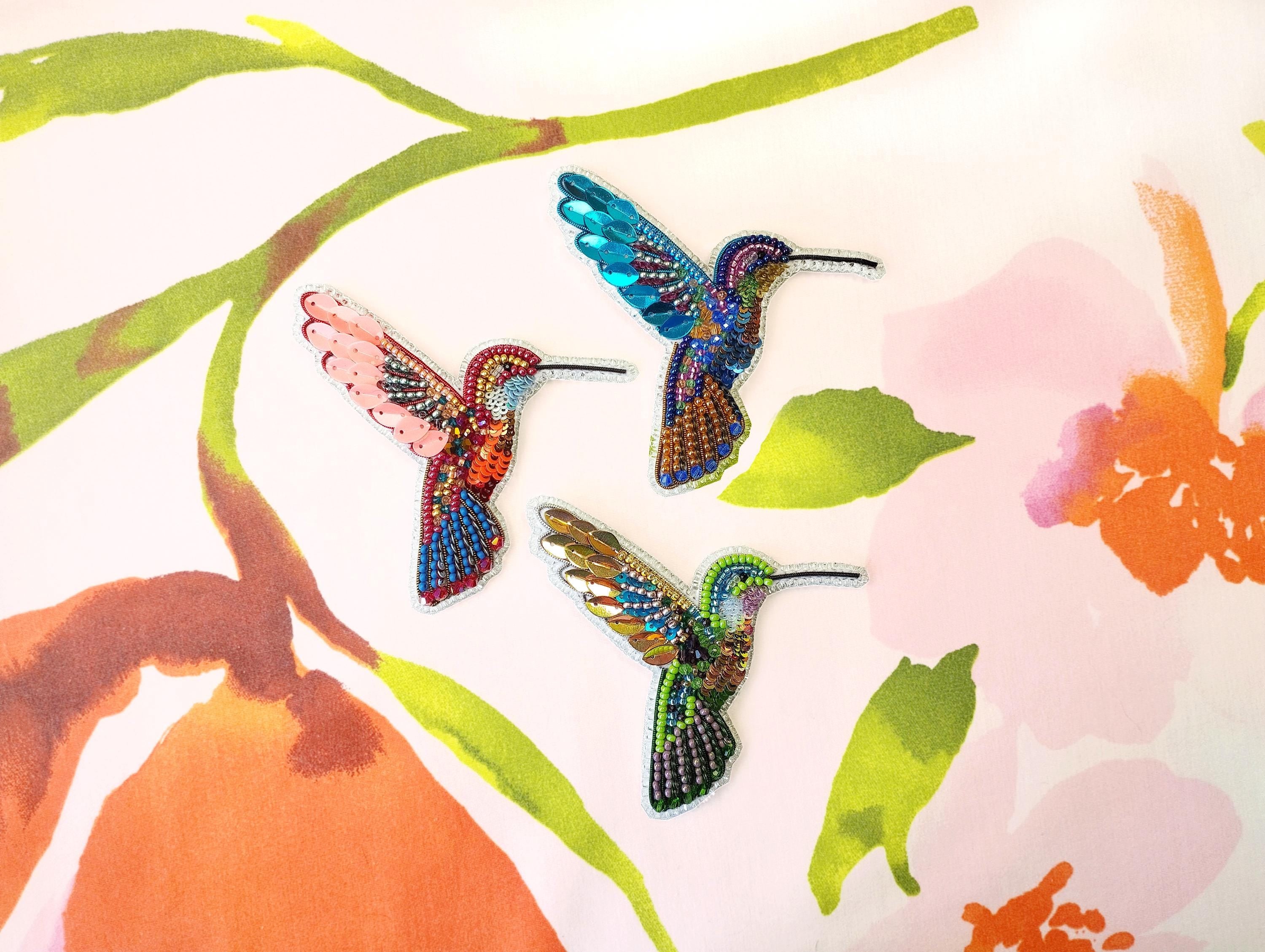 three colorful birds sitting on top of a flower covered wall